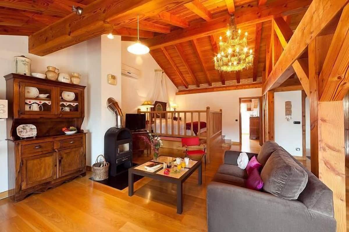 A cozy living room with a fireplace, wooden furniture, and a chandelier.