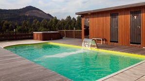 A wooden deck with a swimming pool, a hot tub, and a wooden building with two doors. - Las casas de Ea Astei (Ea)