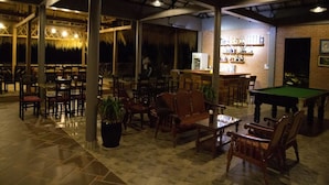 An indoor bar area with tables, chairs, a pool table, and a bar counter with shelves of bottles. - Salty River Resort (Kampot)