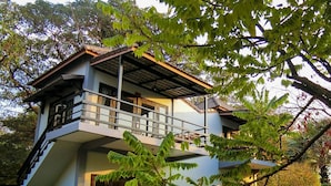 A two-story building with a balcony, surrounded by lush greenery and a stone pathway. - Salty River Resort (Kampot)