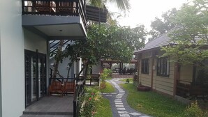A pathway leading to a building with a covered outdoor seating area and a small garden. - Salty River Resort (Kampot)