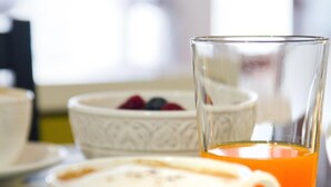 A breakfast setting with a cup of coffee, a glass of orange juice, and a bowl of fruit on a striped table.