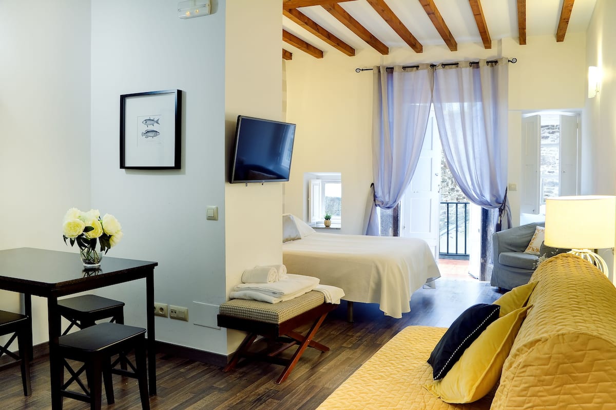 A room with a bed, a desk, a chair, a TV, and a window with curtains.