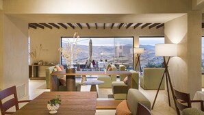 Un espacio habitable amplio con una mesa de comedor de madera, asientos cómodos y ventanas grandes que ofrecen vistas al exterior.