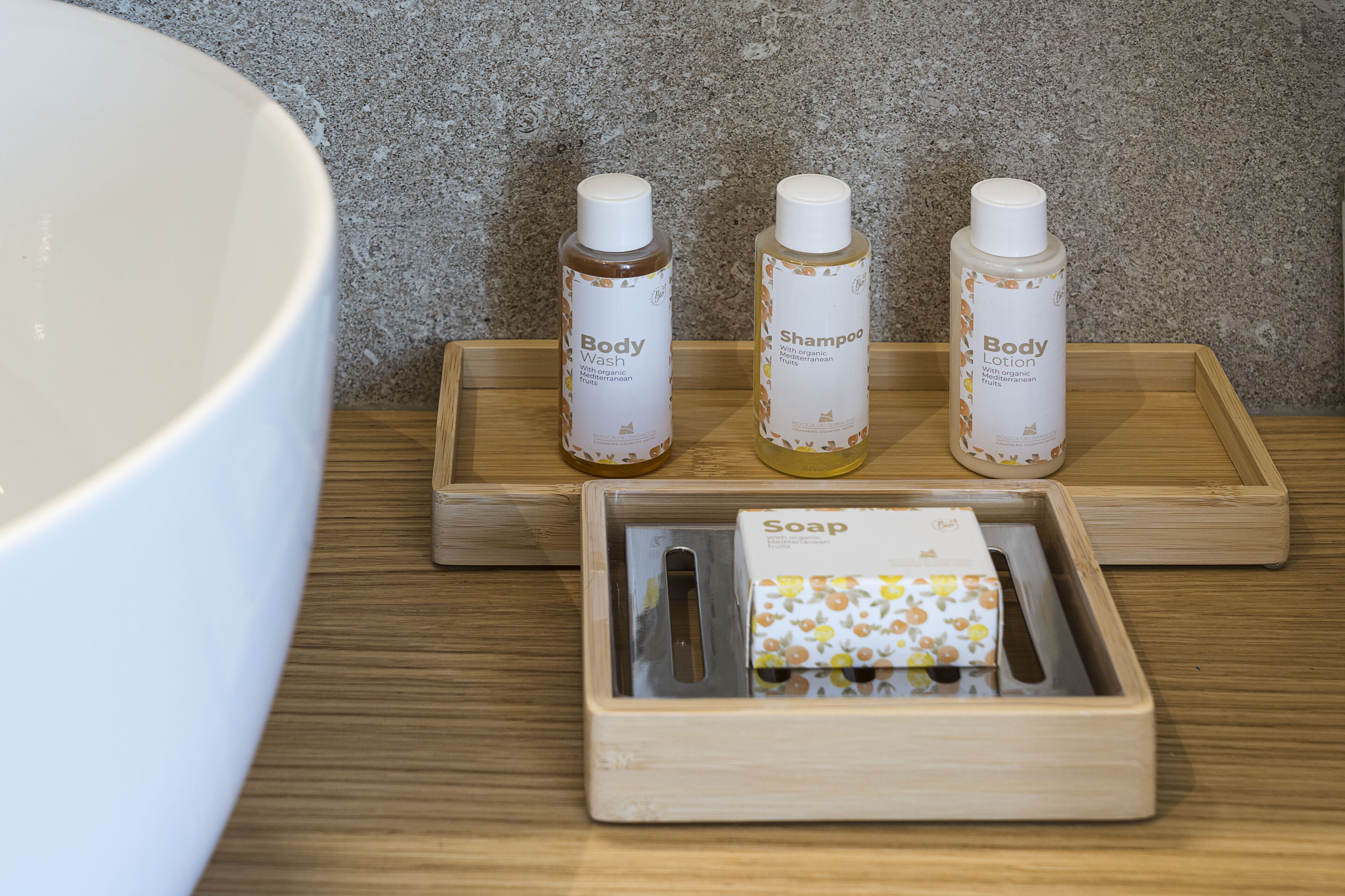 A wooden tray with three bottles of body wash and lotion, and a soap bar on a wooden surface.