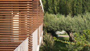 Un edificio moderno con fachada de madera en listones y vistas a un exuberante jardín con árboles y arbustos.