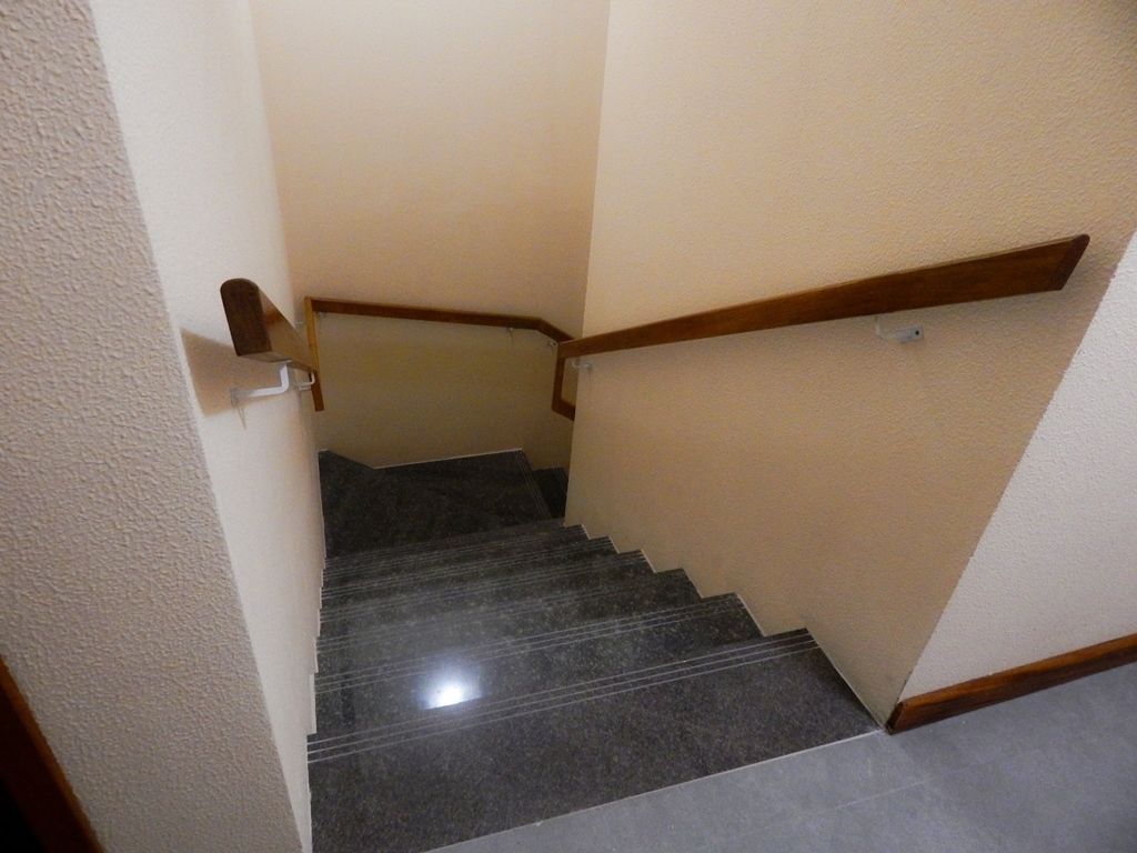 A staircase with dark marble steps and wooden handrails.