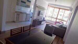 Una cocina moderna con armarios blancos y un comedor con mesa de vidrio y sillas de madera.