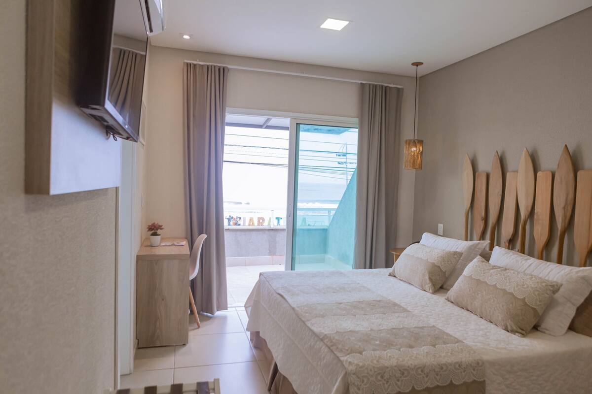 A bedroom with a bed, a desk, and a view of the outside.