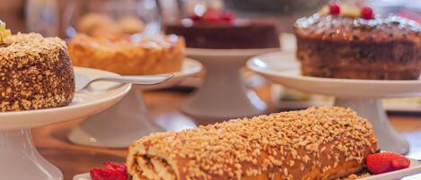 A variety of desserts on white cake stands, including a rolled pastry with nuts and a chocolate cake with berries.