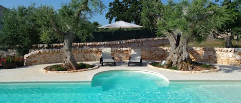 Una piscina al aire libre de temporada, sombrillas, tumbonas