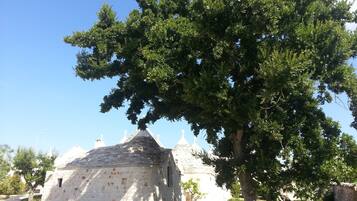 Un edificio in pietra con tetto a cono, circondato da alberi e un cielo azzurro intenso.