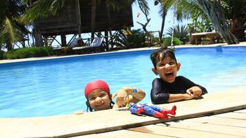 Relax by the pool surrounded by lush greenery and lounge chairs.