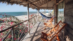 Una terraza de madera con techo de paja que da a la playa.
