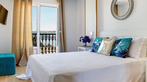 A hotel room with a bed, a small table with a vase of flowers, a mirror on the wall, and a balcony with curtains. - Apartamentos Duerming Sea View Viveiro (Viveiro)