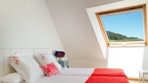 A bedroom with a bed, a nightstand, a window, and a view of a forest. - Apartamentos Duerming Sea View Viveiro (Viveiro)