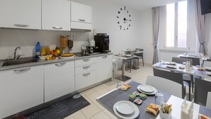 A modern kitchen with white cabinets, a coffee machine, and a dining area with a table set for two. - Trevi Elite Rome (Rome)