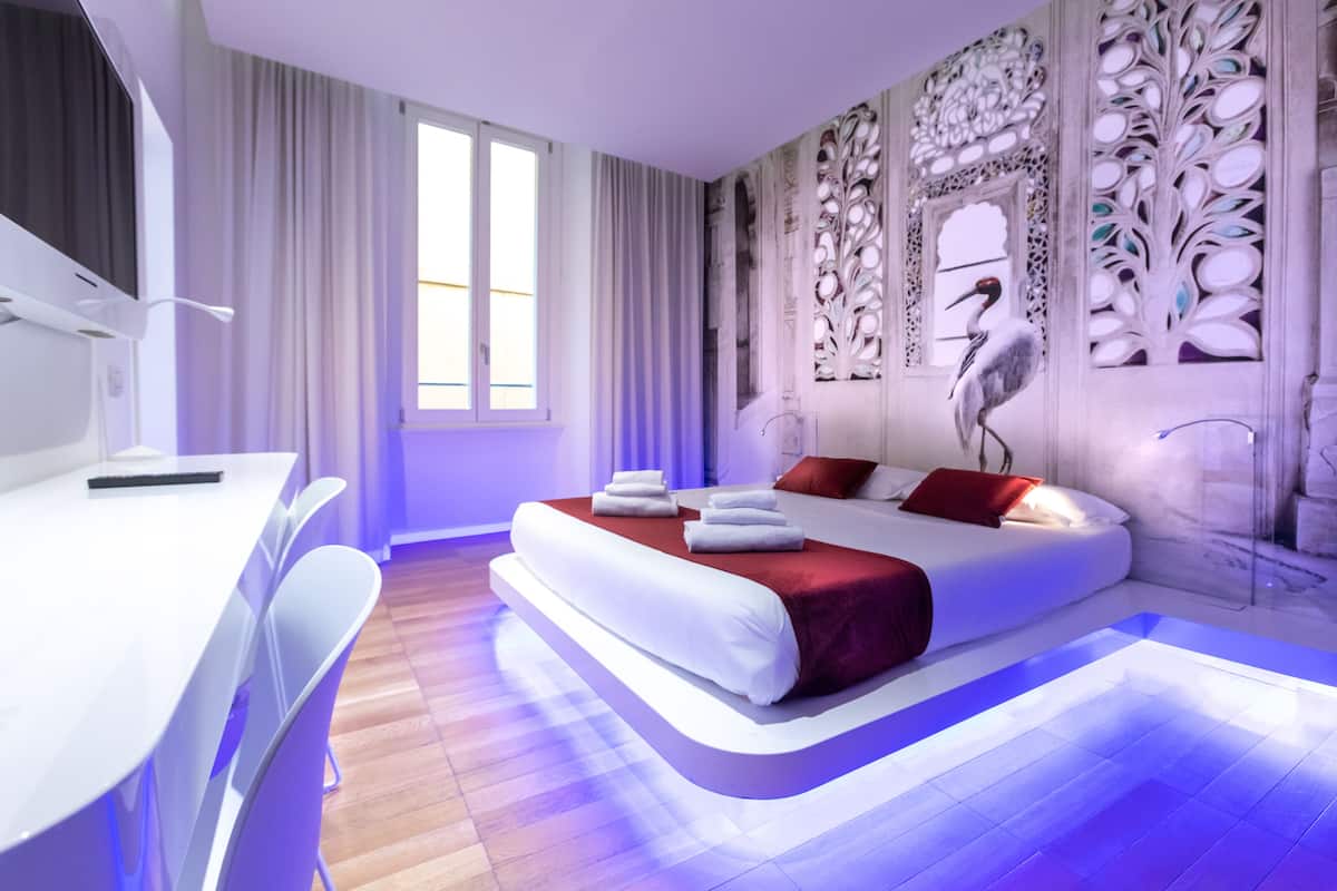 Una habitación de hotel moderna con una cama grande, un escritorio y una silla.