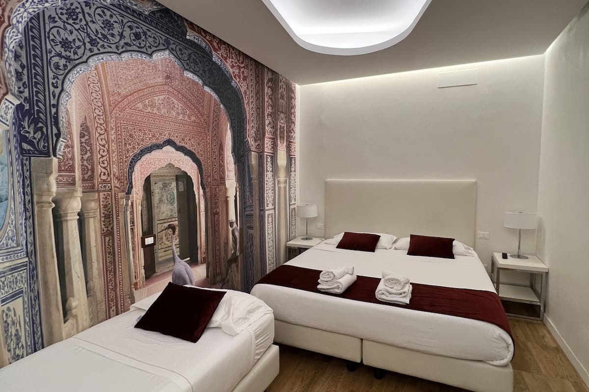 Una habitación de hotel moderna con dos camas, un tragaluz y un mural decorativo en la pared.