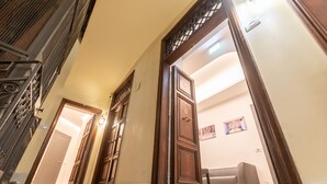 A hallway with a wooden door, a light fixture, and a modern sofa in the background. - Trevi Elite Rome (Rome)