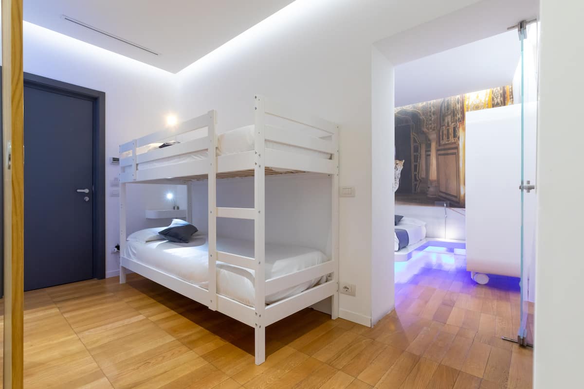 Habitación con literas, un escritorio pequeño y una pared con un cuadro.