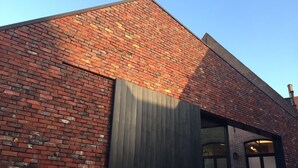 A brick building with a large window and a slanted roof. - B-Square Brugge (Bruges)