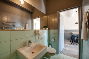 A modern bathroom with a sink, toilet, and a mirror. There is a towel rack and a small plant on the counter. - Smiltynes Jachtklubas (Klaipeda)