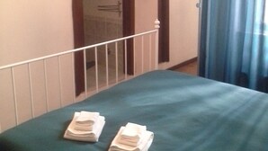 A hotel room with a bed, a door, and a window with curtains. - Roman Enchantment (Rome)