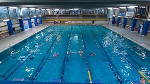 A large indoor swimming pool with multiple lanes, a diving platform, and a spectator area. - Roman Enchantment (Rome)