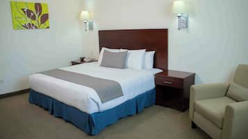 Camera d'albergo con un letto grande, due lampade ai comodini, una scrivania, una sedia e un quadro appeso al muro.