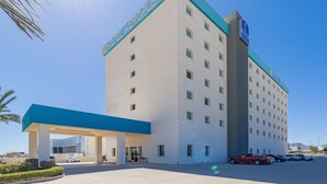A hotel with a prominent sign reading "HOTEL AEROPORTO" and a blue and white color scheme.