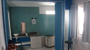A bedroom with a bed, a ceiling fan, a window with curtains, a bathroom with a sink and mirror, and a small table with a vase. - Albergue Piratas do Sol - Hostel (Recife)