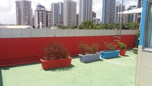 A rooftop terrace with potted plants and a red wall. - Albergue Piratas do Sol - Hostel (Recife)