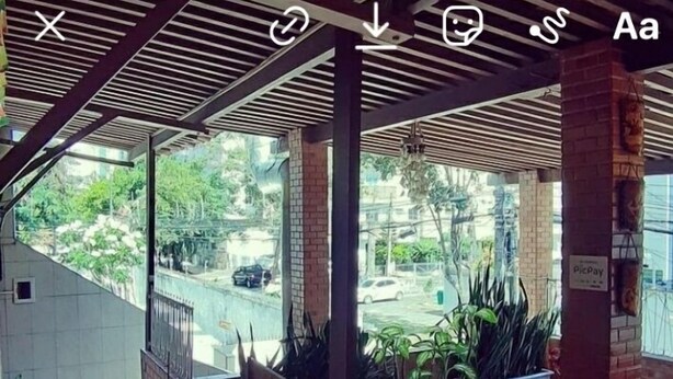 A covered outdoor seating area with brick pillars, potted plants, and a view of the street. - Albergue Piratas do Sol - Hostel (Recife)
