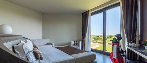 A modern hotel room with a large bed, a desk, and a view of the outdoors.