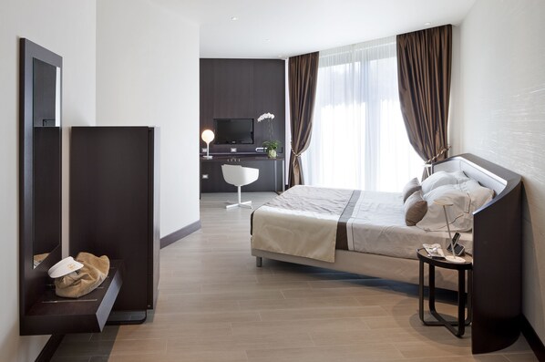 A modern hotel room with a bed, a desk, a TV, and a wardrobe. - Isola di Albarella Golf Hotel (Rosolina)