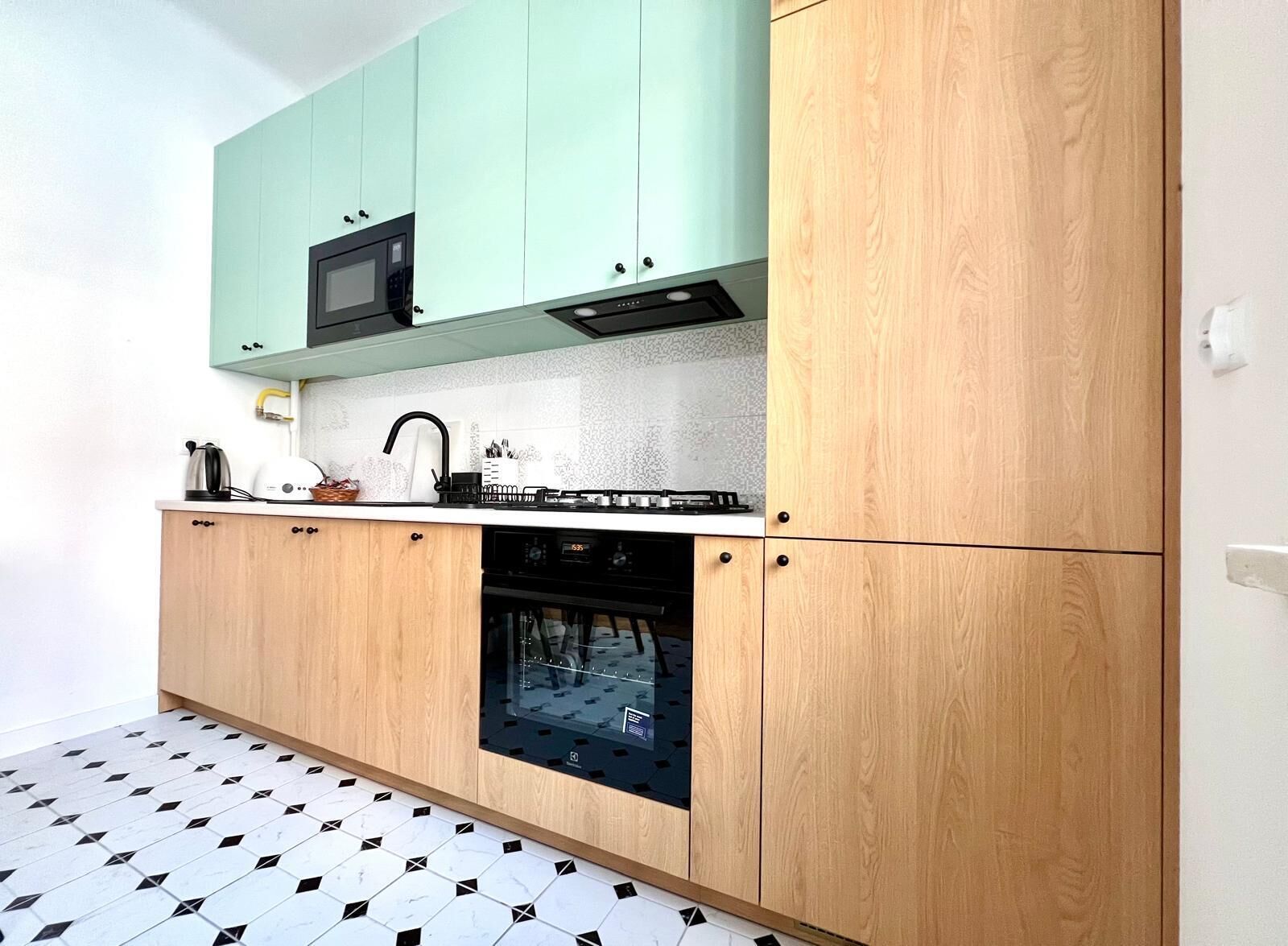 A compact kitchen with a microwave, kettle, and oven.