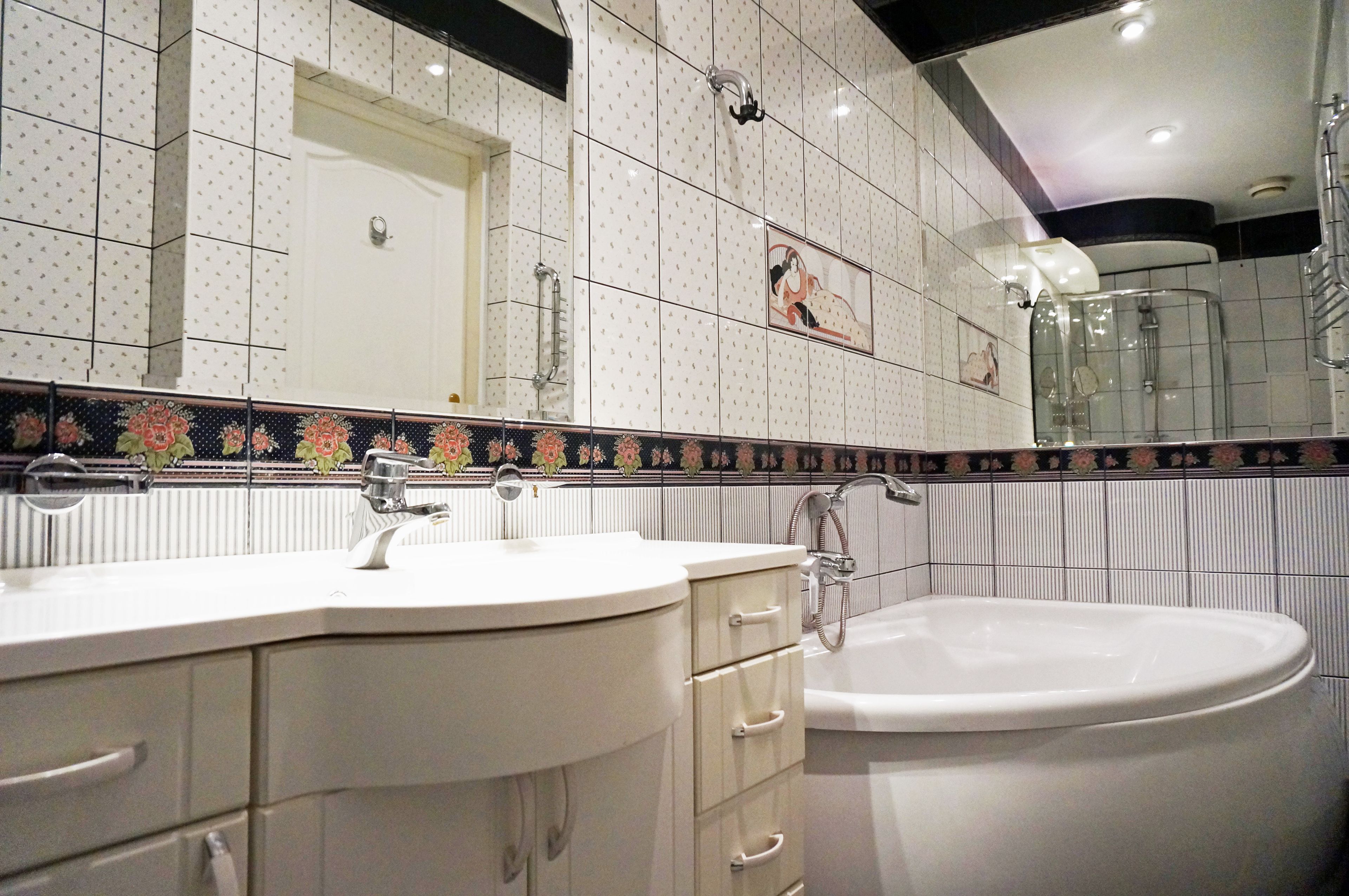 A bathroom with a white sink, vanity, and bathtub.