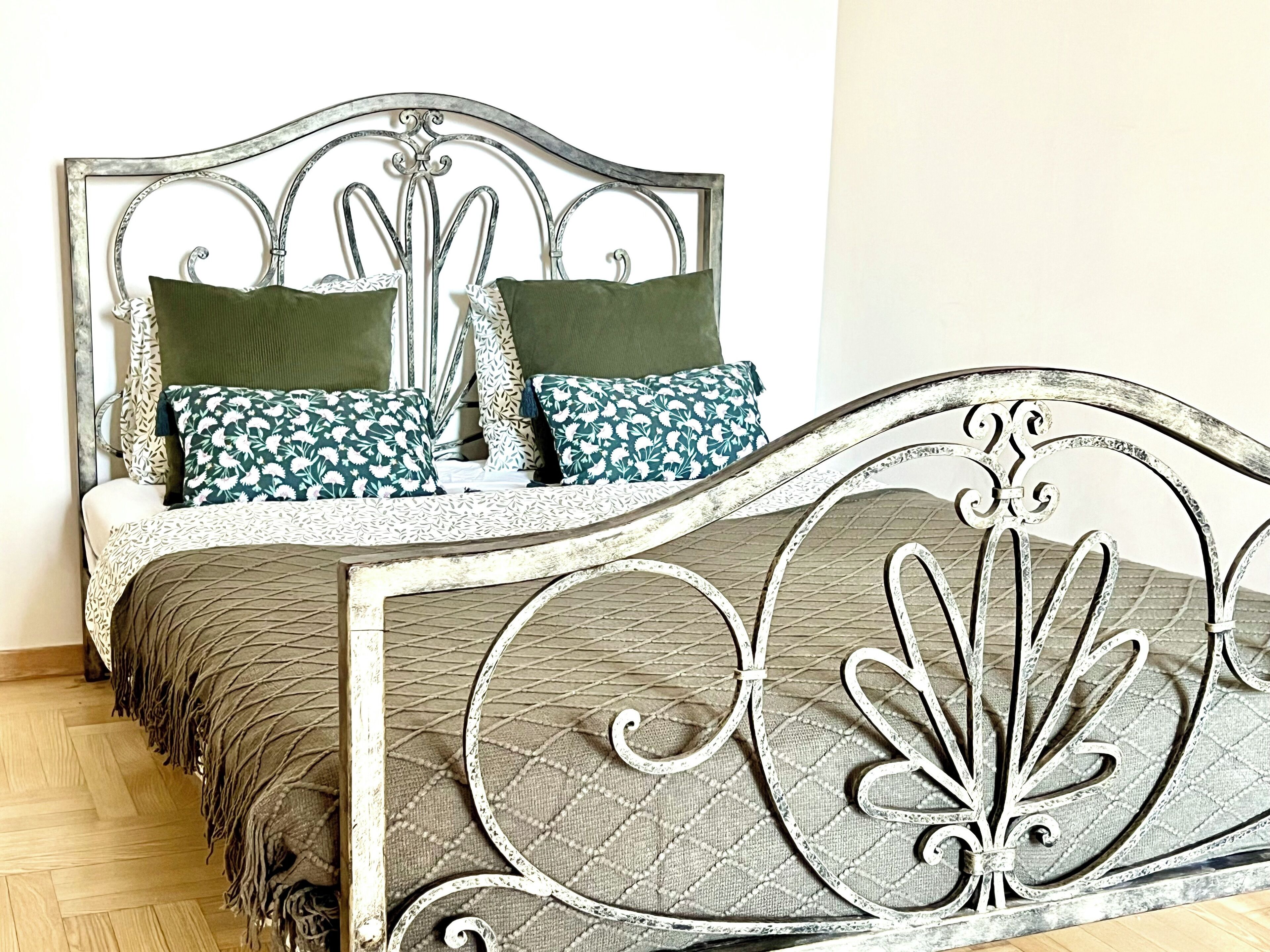 A bed with a metal frame and patterned bedding.