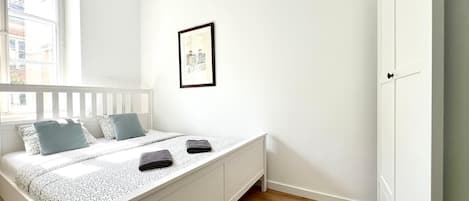 Un dormitorio con una cama, un armario blanco y un cuadro en la pared.