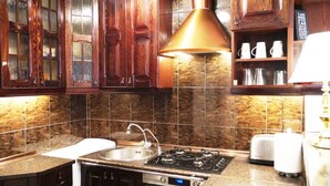 Una cocina con armarios de madera, un lavamanos de acero inoxidable, una estufa a gas y un tostador.