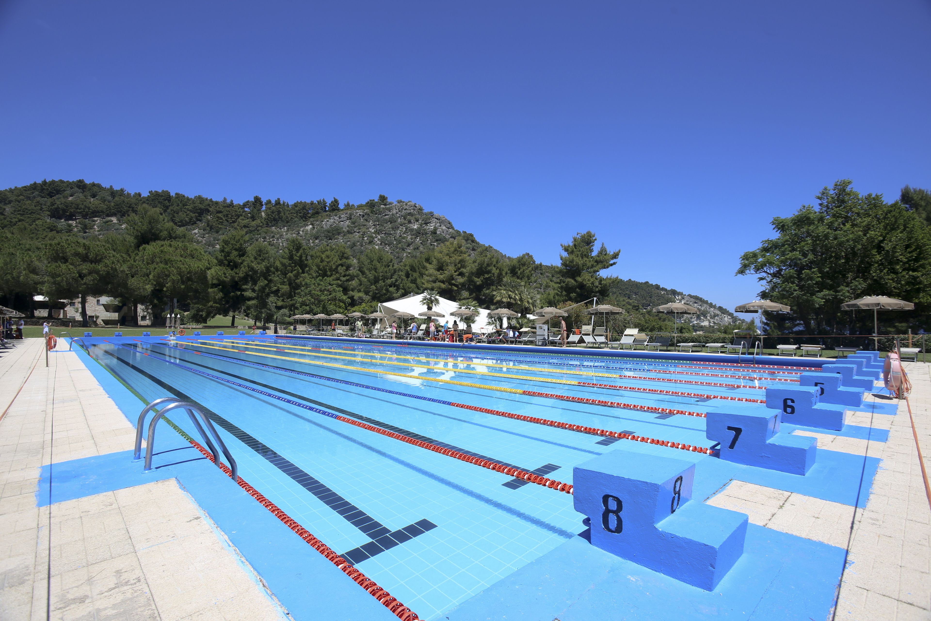 Una piscina con carriles marcados por números y un área de solárium con baldosas.