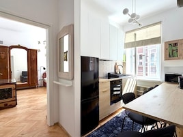 Une cuisine moderne avec un réfrigérateur noir, des meubles de rangement en bois, une table à manger avec des chaises et une grande fenêtre donnant sur un beau paysage.