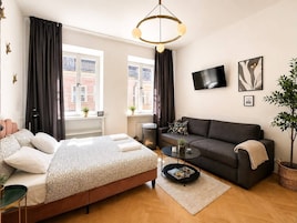 Un dormitorio moderno con una cama, un sofá, una mesa de centro y un televisor.