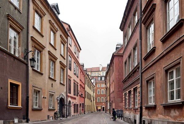A narrow street lined with multi-story buildings, featuring arched doorways and uniform windows.