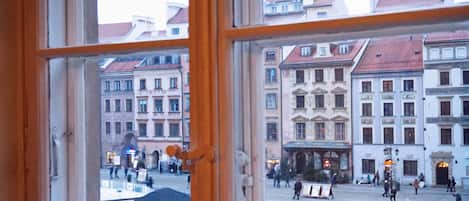 A view through a window of a historic building with multiple floors, large windows, and a courtyard with people.