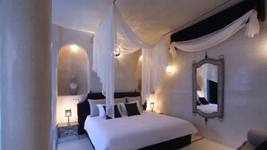 A bedroom with a large bed, a bedside table, a wall-mounted mirror, and a decorative vase. - Riad Joya (Marrakech)