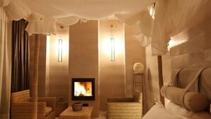 A cozy room with a fireplace, comfortable seating, and elegant decor. - Riad Joya (Marrakech)
