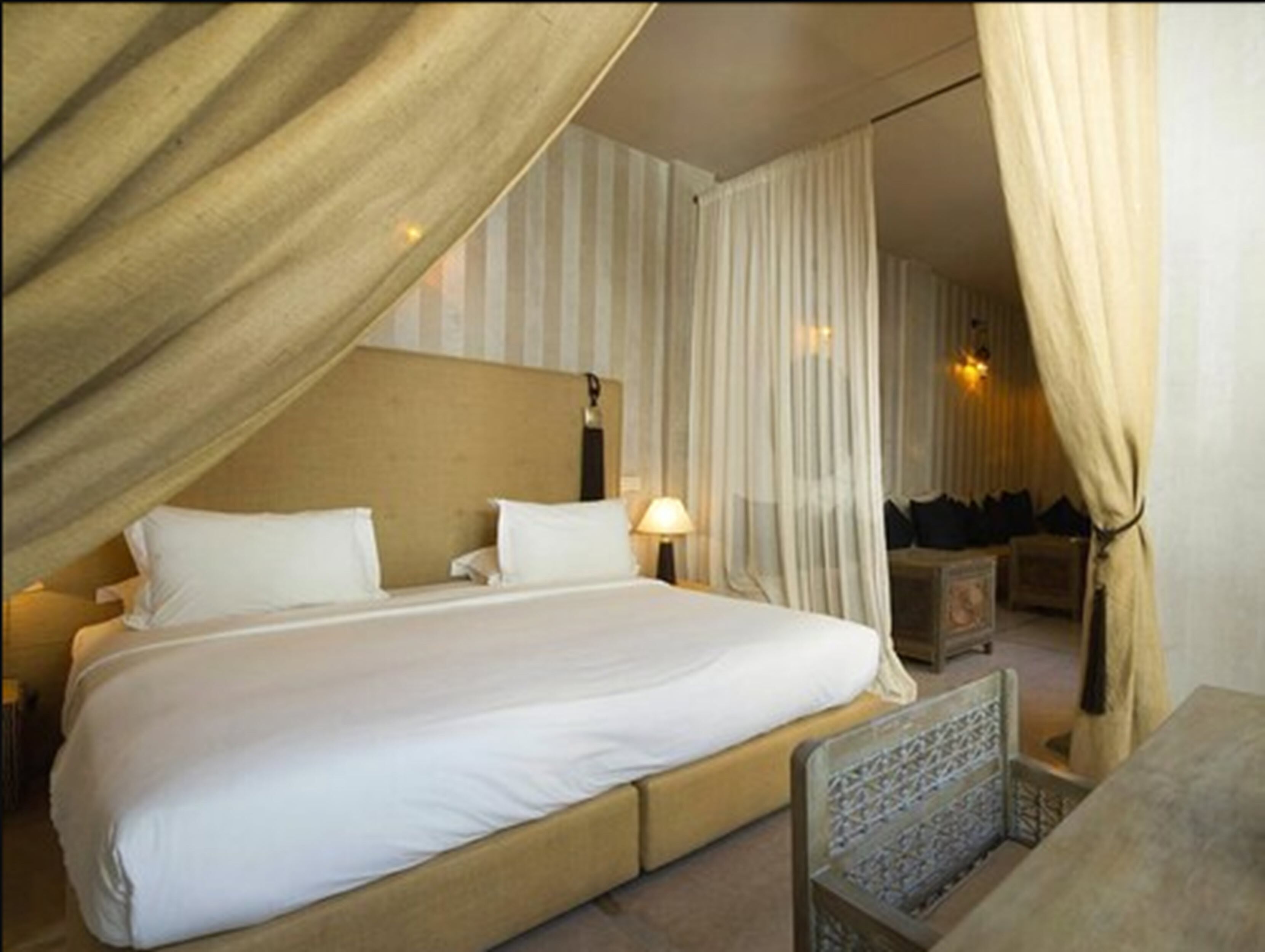 Une chambre à coucher avec un grand lit, une table de chevet, une lampe et une chaise.