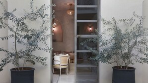 A doorway leading to a dining area with a table and chairs, flanked by two large potted plants. - Riad Joya (Marrakech)
